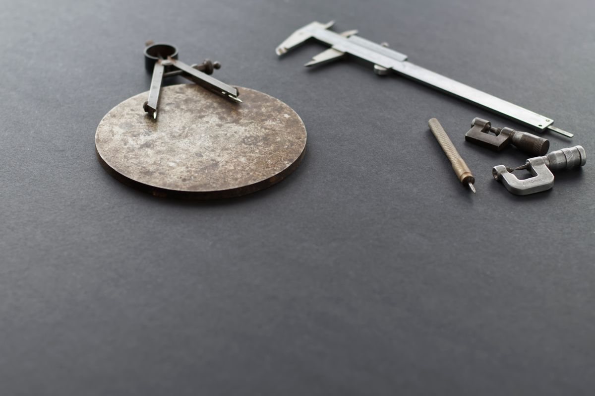 Gedrehtes Bauteil mit Messschieber und Zirkel auf der Werkbank